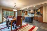 Experience comfortable dining and cooking in this spacious kitchen and dining area, featuring a large wooden dining table with plush seating and a well-equipped kitchen with a central island.