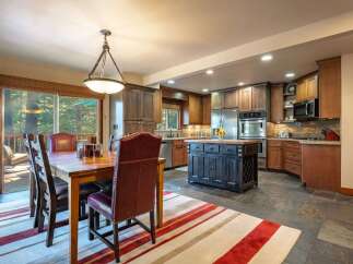 Experience comfortable dining and cooking in this spacious kitchen and dining area, featuring a large wooden dining table with plush seating and a well-equipped kitchen with a central island.