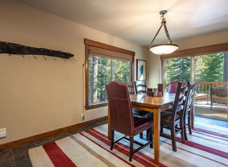 Experience rustic charm in this inviting dining room, featuring a sturdy wooden table surrounded by comfortable leather and plaid chairs.