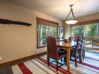 Experience rustic charm in this inviting dining room, featuring a sturdy wooden table surrounded by comfortable leather and plaid chairs.
