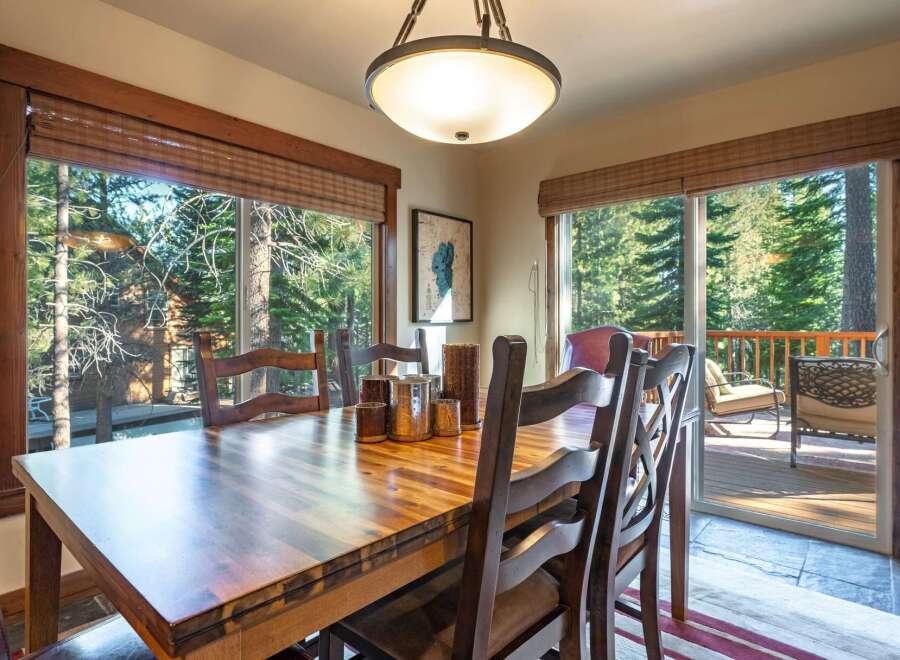 Enjoy breathtaking forest views from this inviting dining room, featuring a large wooden table perfect for family gatherings.