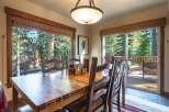 Enjoy breathtaking forest views from this inviting dining room, featuring a large wooden table perfect for family gatherings.