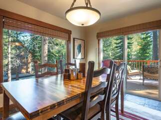 Enjoy breathtaking forest views from this inviting dining room, featuring a large wooden table perfect for family gatherings.