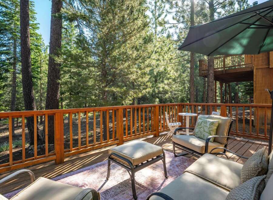 Enjoy the serene mountain lifestyle from this expansive wooden deck, nestled amongst tall pine trees.