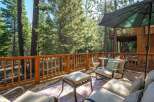 Enjoy the serene mountain lifestyle from this expansive wooden deck, nestled amongst tall pine trees.
