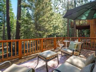 Enjoy the serene mountain lifestyle from this expansive wooden deck, nestled amongst tall pine trees.