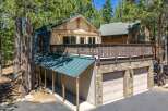 Nestled among tall pine trees, this charming home offers a unique A-frame design with a striking green metal roof.