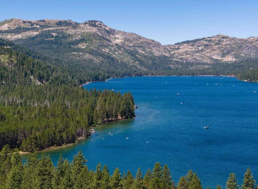 Experience the ultimate lakeside lifestyle with this stunning property offering breathtaking views of a pristine blue lake surrounded by lush green forests and majestic mountains.