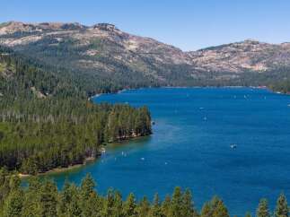 Experience the ultimate lakeside lifestyle with this stunning property offering breathtaking views of a pristine blue lake surrounded by lush green forests and majestic mountains.
