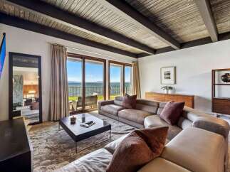 Experience breathtaking lake views from this stunning living room, featuring a spacious sectional sofa perfect for relaxation.