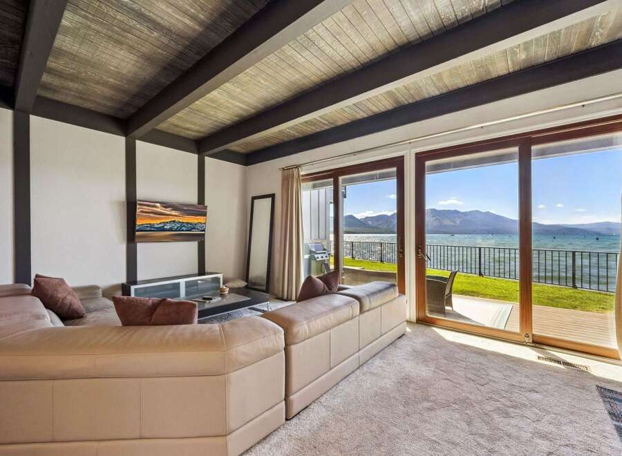 Experience breathtaking lake and mountain views from this stunning living room, featuring a plush sectional sofa perfect for relaxation.