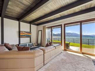 Experience breathtaking lake and mountain views from this stunning living room, featuring a plush sectional sofa perfect for relaxation.