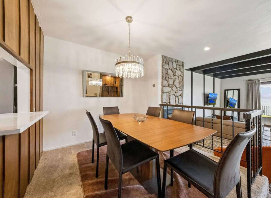 Experience elegant dining with this stylish wooden table, perfectly complemented by modern upholstered chairs.