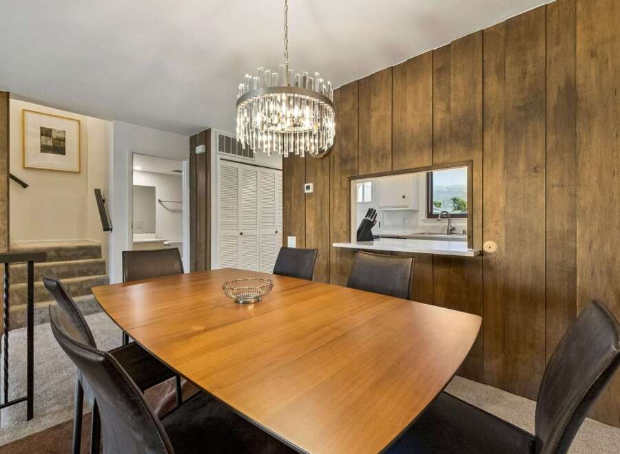 This dining room features a warm and inviting atmosphere with its rich wood-paneled walls and a stylish modern chandelier.