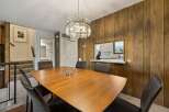 This dining room features a warm and inviting atmosphere with its rich wood-paneled walls and a stylish modern chandelier.