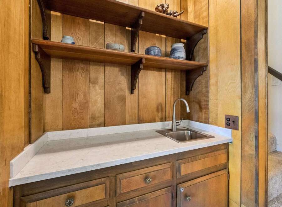 Discover a charming wet bar area featuring a stainless steel sink and elegant quartz countertops, perfect for entertaining.