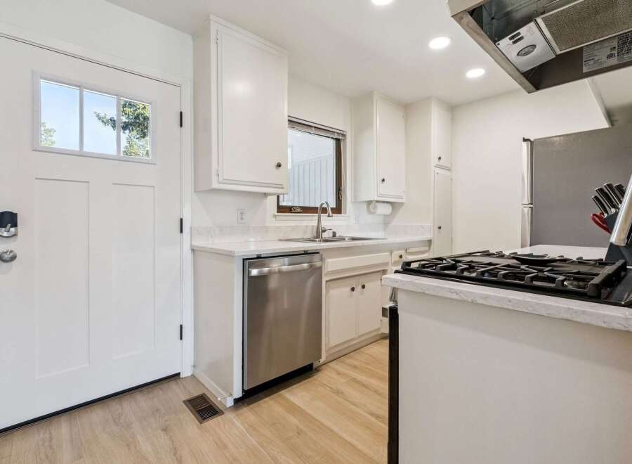 Discover this charming kitchen featuring crisp white cabinetry and sleek stainless steel appliances, including a dishwasher and a gas range.