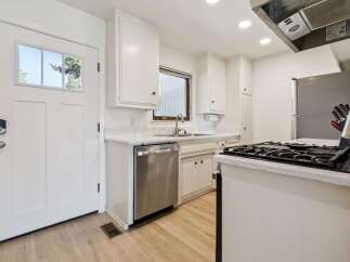 Discover this charming kitchen featuring crisp white cabinetry and sleek stainless steel appliances, including a dishwasher and a gas range.