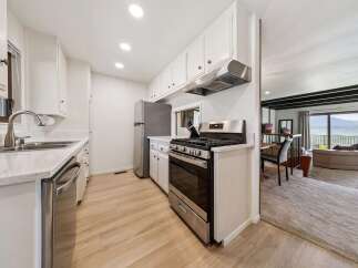 Discover this charming kitchen featuring sleek stainless steel appliances, including a modern gas range and a dishwasher.