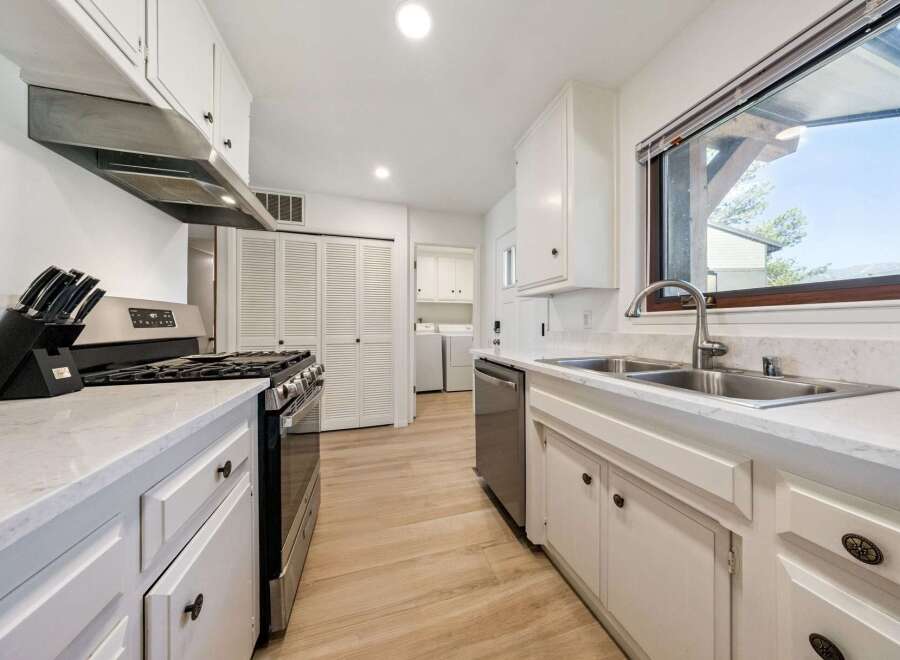 Discover this charming kitchen featuring a sleek stainless steel gas range and a modern range hood, perfect for culinary enthusiasts.