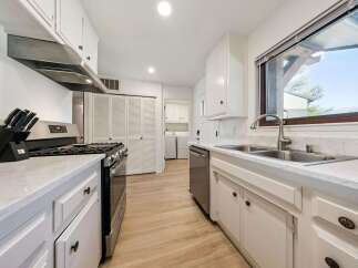 Discover this charming kitchen featuring a sleek stainless steel gas range and a modern range hood, perfect for culinary enthusiasts.