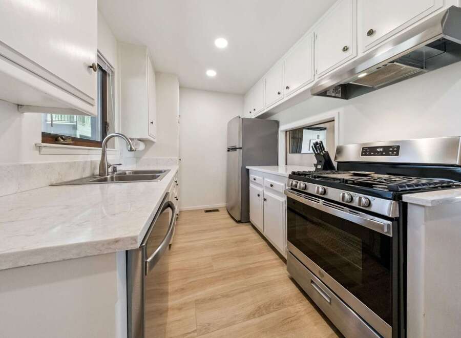 This galley kitchen features a sleek stainless steel gas range with a matching range hood, perfect for the home chef.