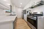 This galley kitchen features a sleek stainless steel gas range with a matching range hood, perfect for the home chef.