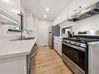 This galley kitchen features a sleek stainless steel gas range with a matching range hood, perfect for the home chef.