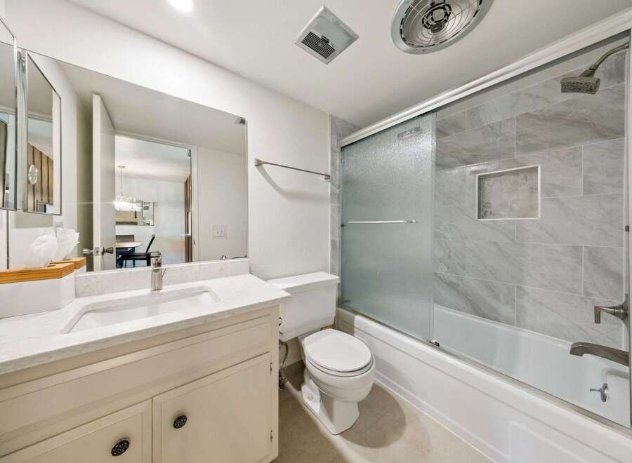 This modern bathroom features a sleek vanity with a marble countertop and a large mirror, perfect for your morning routine.