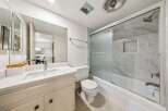 This modern bathroom features a sleek vanity with a marble countertop and a large mirror, perfect for your morning routine.