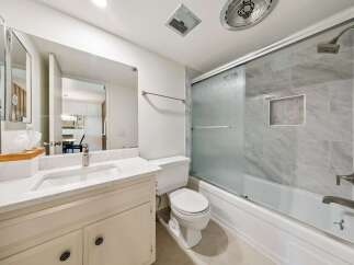 This modern bathroom features a sleek vanity with a marble countertop and a large mirror, perfect for your morning routine.