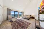 Experience breathtaking lake views from this luxurious master suite, featuring a comfortable recliner and a large bed.