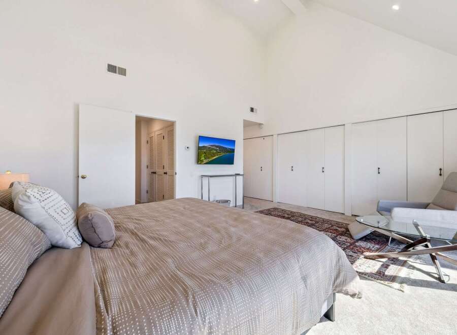 This spacious bedroom features a vaulted ceiling and ample natural light, creating an airy and inviting atmosphere.