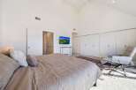 This spacious bedroom features a vaulted ceiling and ample natural light, creating an airy and inviting atmosphere.
