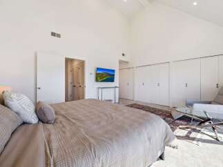 This spacious bedroom features a vaulted ceiling and ample natural light, creating an airy and inviting atmosphere.