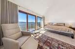 Experience breathtaking lake views from this luxurious bedroom, featuring expansive sliding glass doors that open to a private balcony.