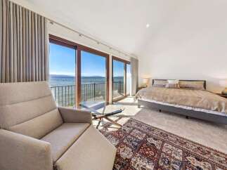 Experience breathtaking lake views from this luxurious bedroom, featuring expansive sliding glass doors that open to a private balcony.