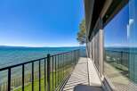 Experience breathtaking lakefront living from this stunning balcony, offering panoramic views of the sparkling blue water and distant mountains.