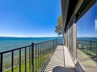 Experience breathtaking lakefront living from this stunning balcony, offering panoramic views of the sparkling blue water and distant mountains.