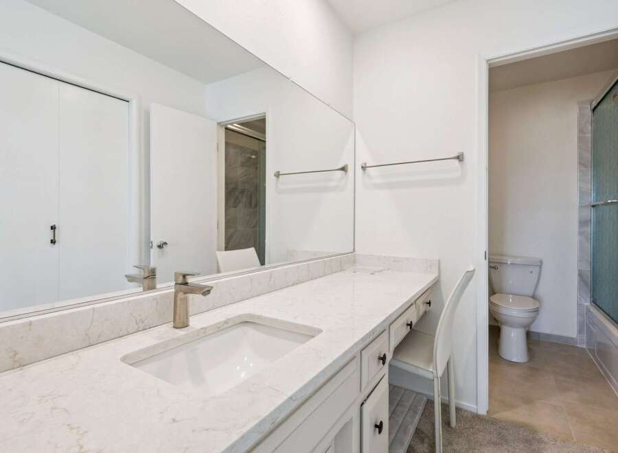 This modern bathroom features a spacious vanity with a sleek countertop and undermount sink, complemented by a large mirror.