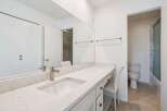 This modern bathroom features a spacious vanity with a sleek countertop and undermount sink, complemented by a large mirror.