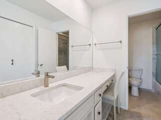 This modern bathroom features a spacious vanity with a sleek countertop and undermount sink, complemented by a large mirror.