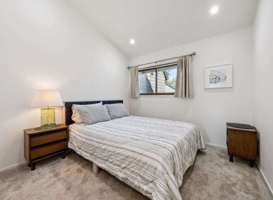 This charming bedroom features a comfortable queen-size bed with a striped comforter and plush pillows, perfect for a restful night's sleep.