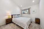 This charming bedroom features a comfortable queen-size bed with a striped comforter and plush pillows, perfect for a restful night's sleep.