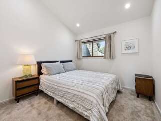 This charming bedroom features a comfortable queen-size bed with a striped comforter and plush pillows, perfect for a restful night's sleep.