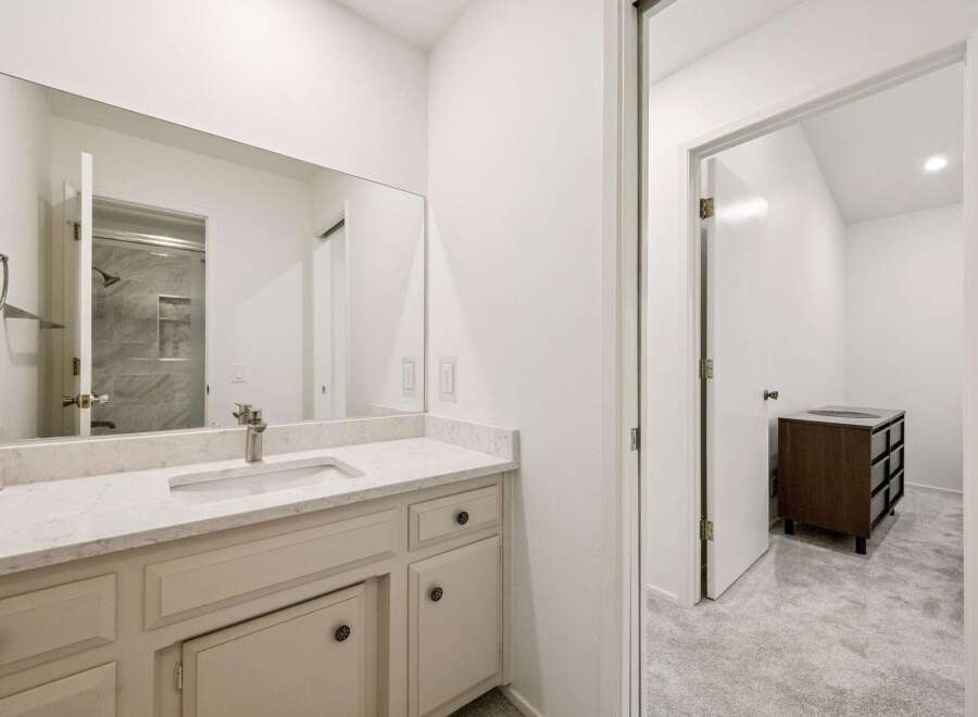 This modern bathroom features a spacious vanity with a sleek countertop and a large mirror, offering ample storage and a bright, airy feel.