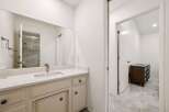 This modern bathroom features a spacious vanity with a sleek countertop and a large mirror, offering ample storage and a bright, airy feel.