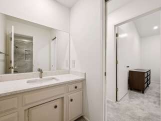 This modern bathroom features a spacious vanity with a sleek countertop and a large mirror, offering ample storage and a bright, airy feel.