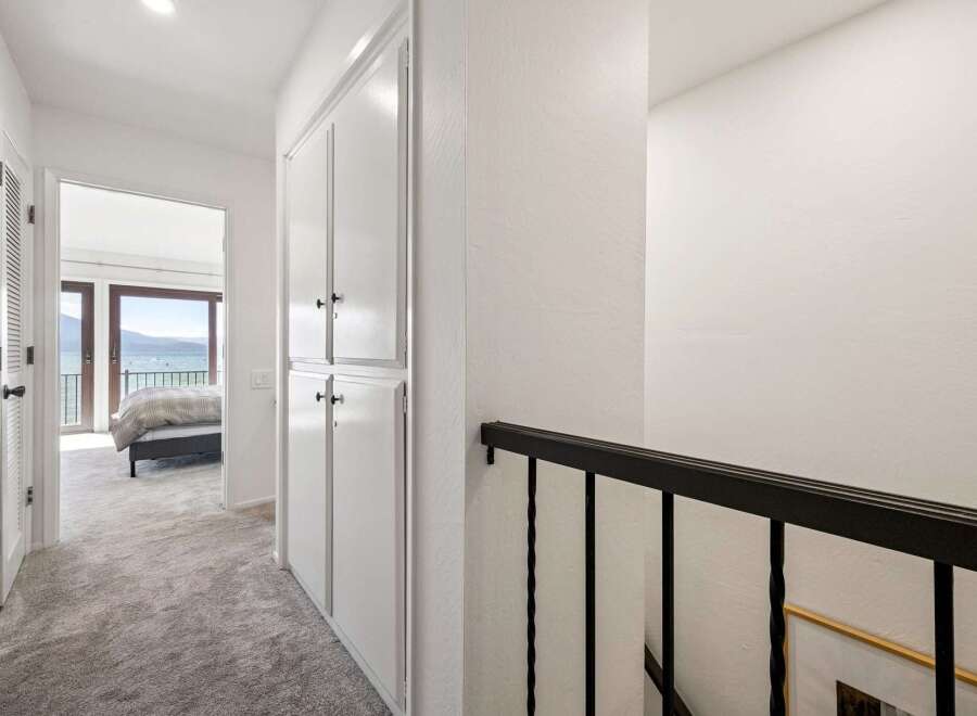 This hallway offers a glimpse into a serene bedroom with stunning lake views through large glass doors.