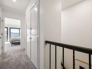 This hallway offers a glimpse into a serene bedroom with stunning lake views through large glass doors.